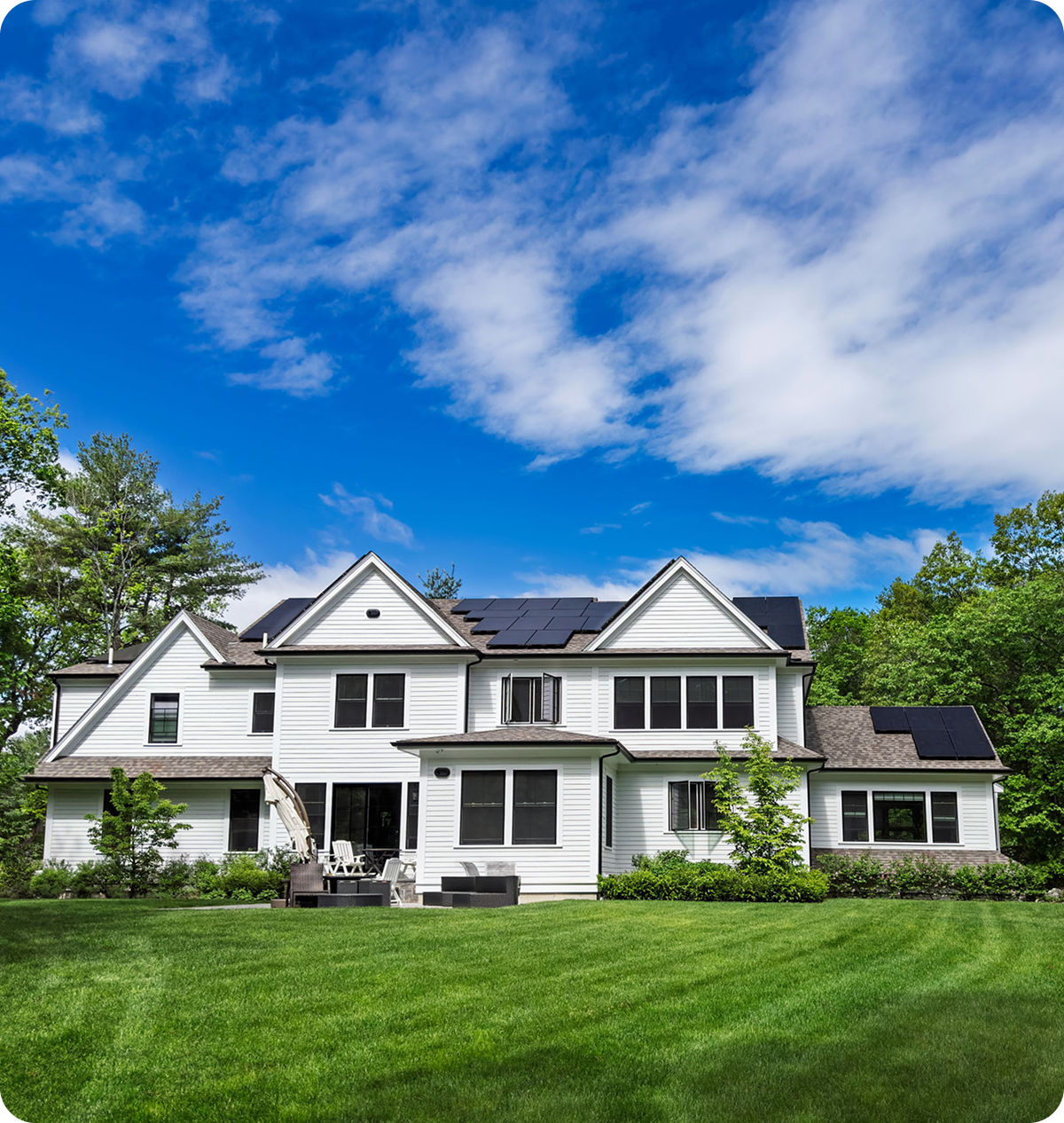 Modern white house with solar panels, lawn.