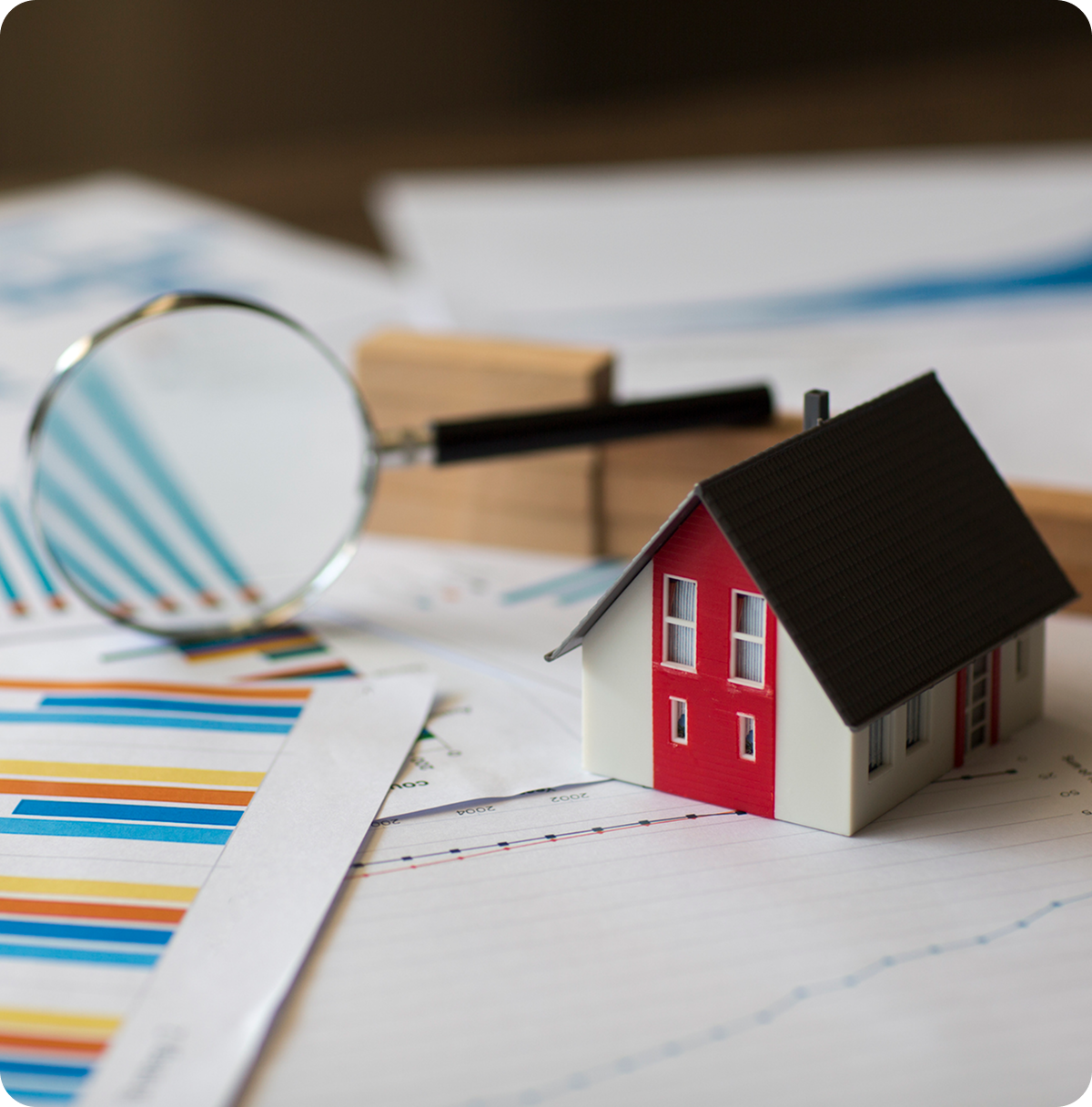 Model house with magnifying glass and charts.