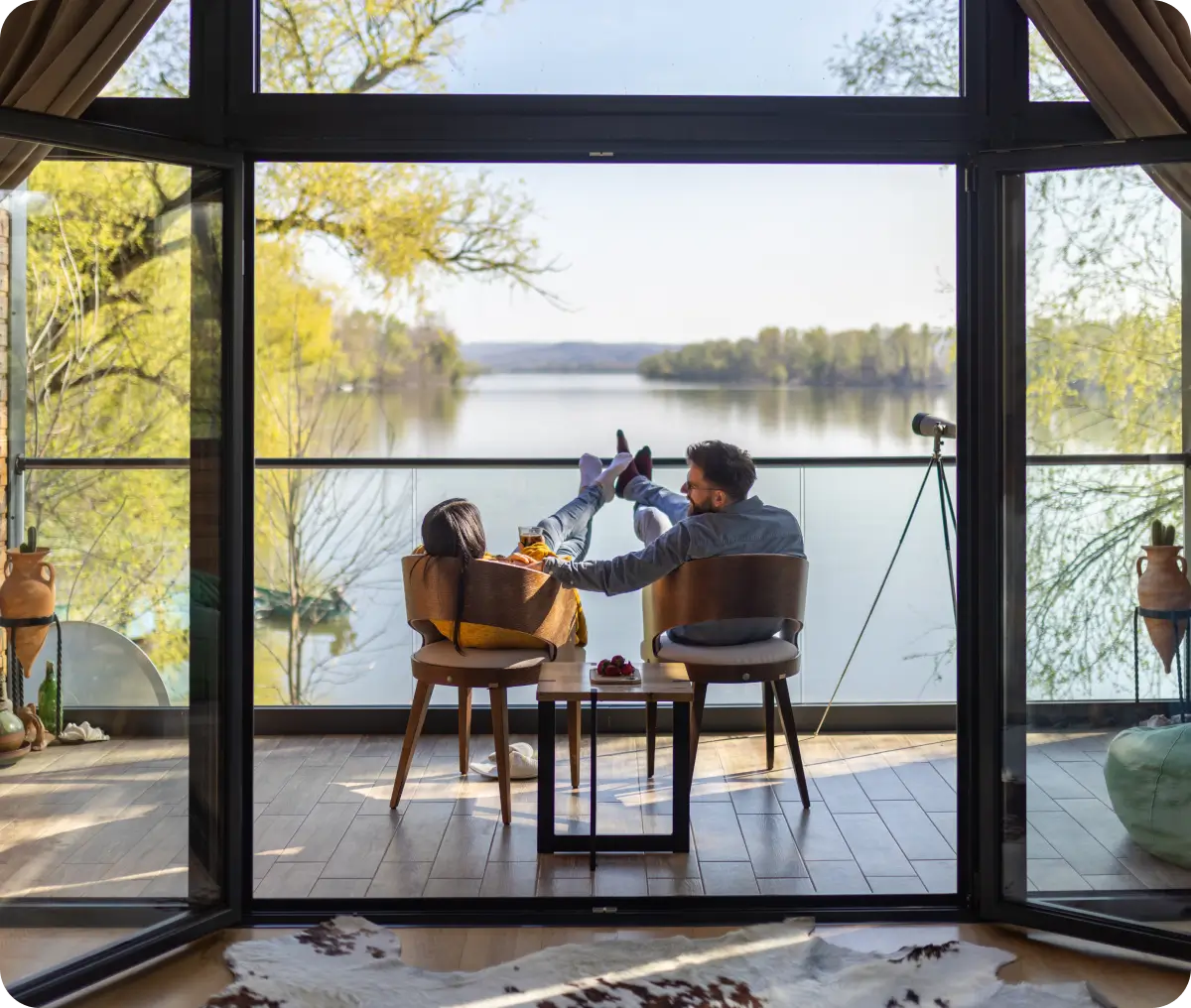 Couple relaxing on balcony overlooking lake.